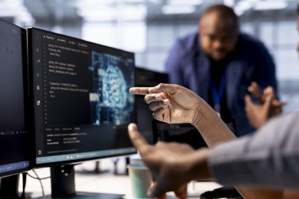 Server farm admin showing colleague AI technology on computer, creating and implementing algorithms. Close up of data center worker pointing finger to artificial intelligence tech on PC