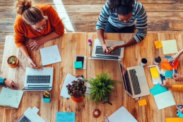 diverse-team-people-working-together-around-table-with-laptops-notebooks-sticky-notes-1-scaled - Modifié