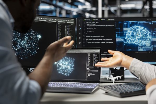 Server farm engineering team looks at data analysis graph to reduce supercomputers failure. Data center coworkers look at AI visualization dashboard to pinpoint gear performance glitches