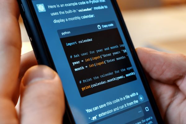 Person holding a smartphone with opened AI chat in it. User asking chat bot to write code in Python